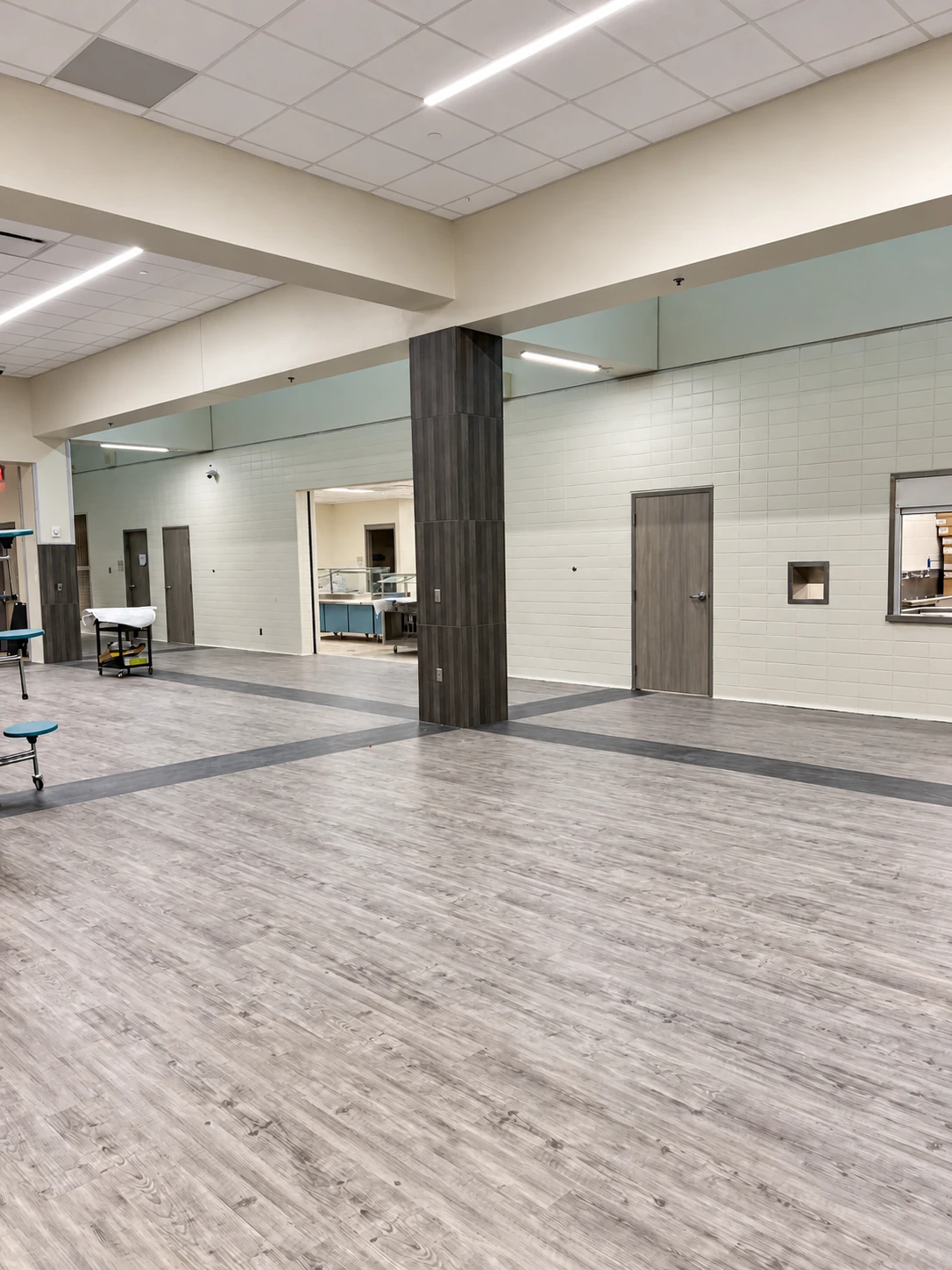 Large commercial interior with wood-look flooring and dark column finishes
